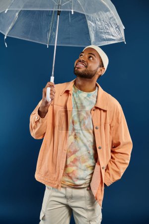 Afro-Américain tenant parapluie clair sous fond vibrant.