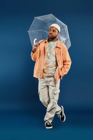African American man in vibrant orange jacket holding clear umbrella.