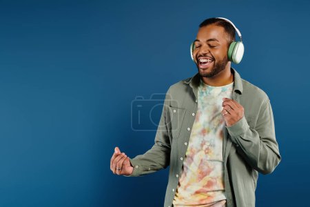 Téléchargez les photos : Stylish man smiling while listening with headphones. - en image libre de droit