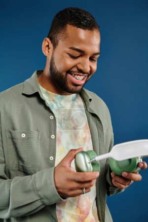 Stylish African American man holding a green and white headphones.
