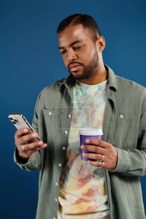 Stylish man browsing phone while sipping coffee.