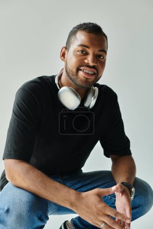 Stylish African American man sits, immersed in music with headphones.