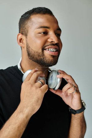 Un hombre afroamericano con una camisa negra con auriculares.