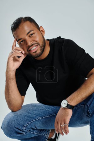 Stylish African American man in black shirt and jeans against a vibrant backdrop.