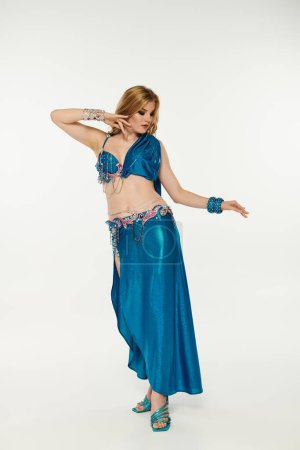 Una mujer elegante en un fascinante traje azul muestra sus habilidades de danza del vientre.