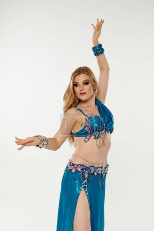 Bezaubernde junge Frau in einem lebendigen blauen Bauchtanzkostüm, das ihre eleganten Bewegungen präsentiert.