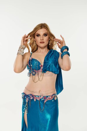 Elegantly dressed young woman showcases belly dance in blue attire.