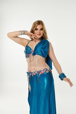 Young woman gracefully demonstrates belly dance in a vibrant blue costume.