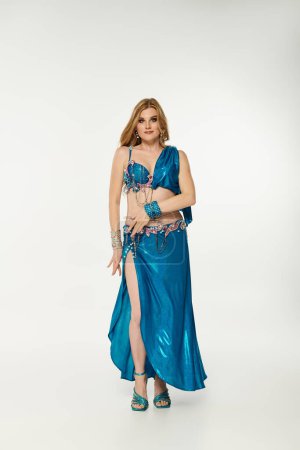 Young woman in blue dress gracefully posing for a dance performance.