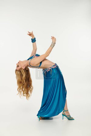 A mesmerizing woman in a blue dress gracefully dances.