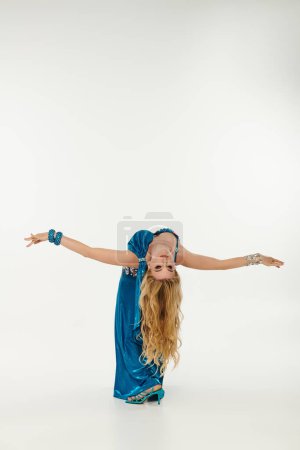 Woman in blue dress gracefully executes a handstand.