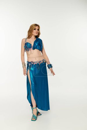 A captivating young woman showcasing her belly dancing skills in a stunning blue costume.