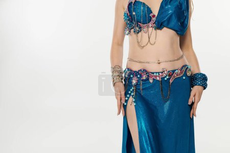 Elegantly dancing, a woman captivates in a stunning blue belly dance costume.