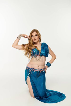 Young woman in a blue dress gracefully posing for a belly dance.
