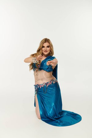 Mujer elegante, vibrante muestra danza del vientre en un traje azul.