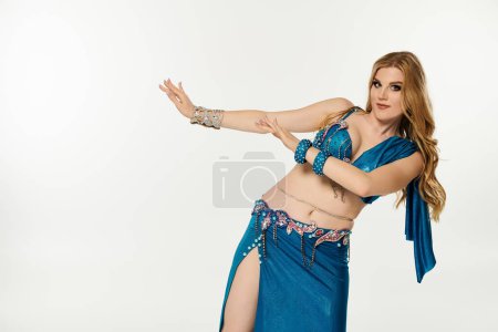 Graceful woman in blue belly dance attire sways elegantly.