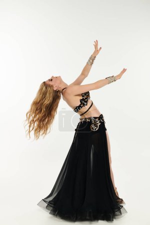 A captivating young woman in a black dress gracefully dancing and swaying.