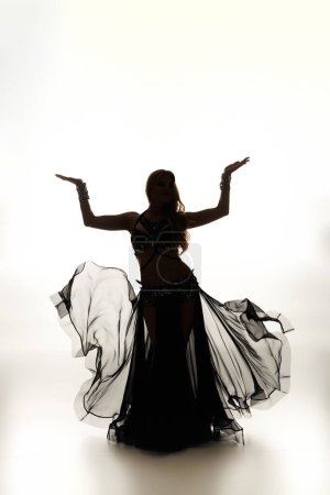A mesmerizing young woman in a black dress gracefully dancing.