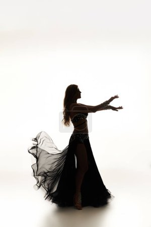 A mesmerizing woman in a black dress gracefully dances.
