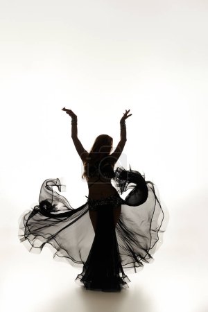 Jeune femme en robe noire effectuant une danse gracieuse.