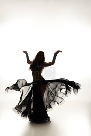 Foto de Una mujer fascinante en un vestido negro baila con gracia. - Imagen libre de derechos