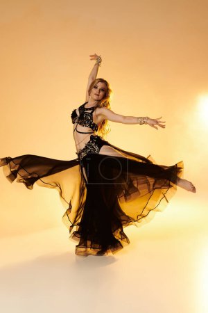 Elegant woman in a black dress showcasing her graceful belly dance moves.
