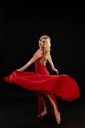 A lady in a red dress gracefully posing.
