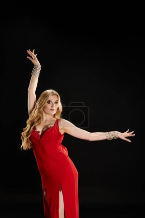 Graceful young woman in a red dress striking a dance pose.