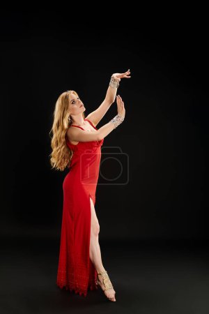 A young woman in a vibrant red dress gracefully poses while performing a dance.