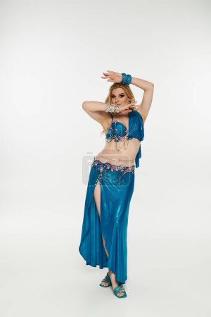Elegantly dancing in vibrant blue belly dance outfit.