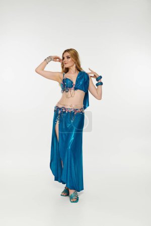 Young woman in captivating blue belly dance costume performing gracefully.