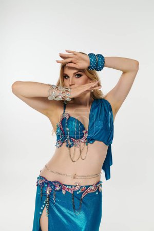 Foto de Mujer joven cautivadoramente ejecuta la rutina de danza del vientre en traje azul. - Imagen libre de derechos