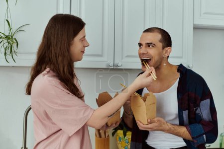 Mann füttert liebevoll einen Partner in gemütlicher häuslicher Umgebung und steht beispielhaft für Fürsorge und Zuneigung zwischen einem homosexuellen Paar.