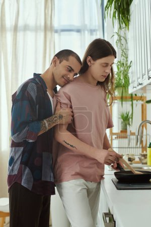 Foto de Una pareja gay vestida con ropa casual está al lado del otro, comprometida en una conversación y preparación de alimentos en una cocina cálida y acogedora.. - Imagen libre de derechos