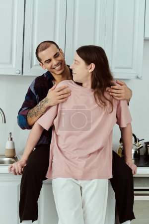 Photo for A gay couple in casual clothes warmly embrace in a kitchen, sharing a moment of love and togetherness. - Royalty Free Image