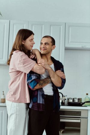 A gay couple, dressed casually, stand together in a warm kitchen, enjoying each others company.