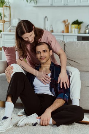 Photo for A gay couple in casual clothes sitting together on the floor of their living room, enjoying quality time as partners. - Royalty Free Image