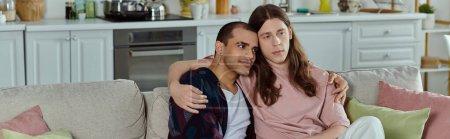 Téléchargez les photos : Un couple gay, assis ensemble sur un canapé confortable, partageant un moment d'amour et de convivialité. - en image libre de droit