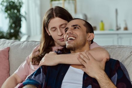 Photo for Lgbt couple in casual clothes, share a warm embrace while sitting on a couch, displaying affection and intimacy. - Royalty Free Image