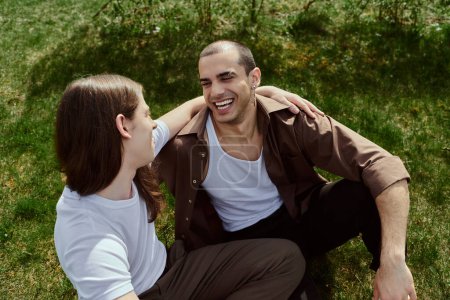 Photo for Lgbt couple in casual attire, enjoying a peaceful moment together while seated on the grass. - Royalty Free Image