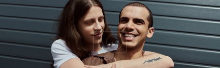 Téléchargez les photos : Un couple gay, portant des vêtements décontractés, s'embrassant à l'extérieur. - en image libre de droit