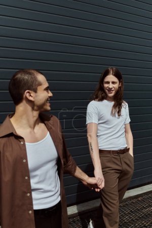 Un couple gay en tenue décontractée marche main dans la main dans une rue urbaine animée, profitant mutuellement de la compagnie et de l'énergie des citys.