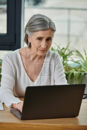 A woman sitting at a laptop, fully focused on work.