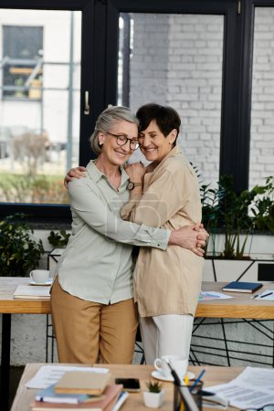 Two women in office, sharing a warm hug.