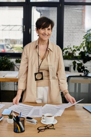 A woman standing in front of a table covered with papers.