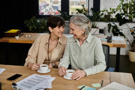 Photo for Two mature women enjoying coffee together at a table. - Royalty Free Image
