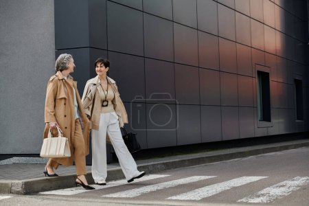Dos mujeres cruzan graciosamente la calle frente a un majestuoso edificio.