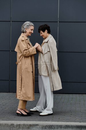 Zwei Frauen posieren elegant zusammen vor einem Gebäude.