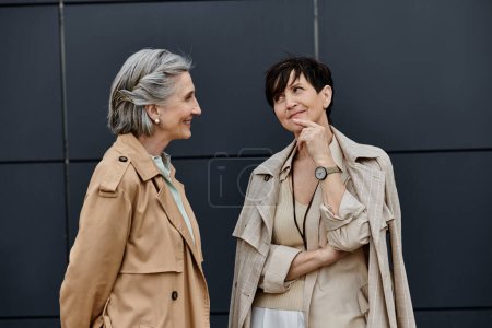 Two mature beautiful women standing together in front of a building.