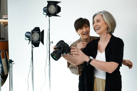 Lesbisches Paar mittleren Alters in einem Fotostudio; eine Frau benutzt eine Kamera
